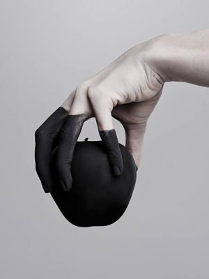Studio shot of a woman's hand holding a black apple